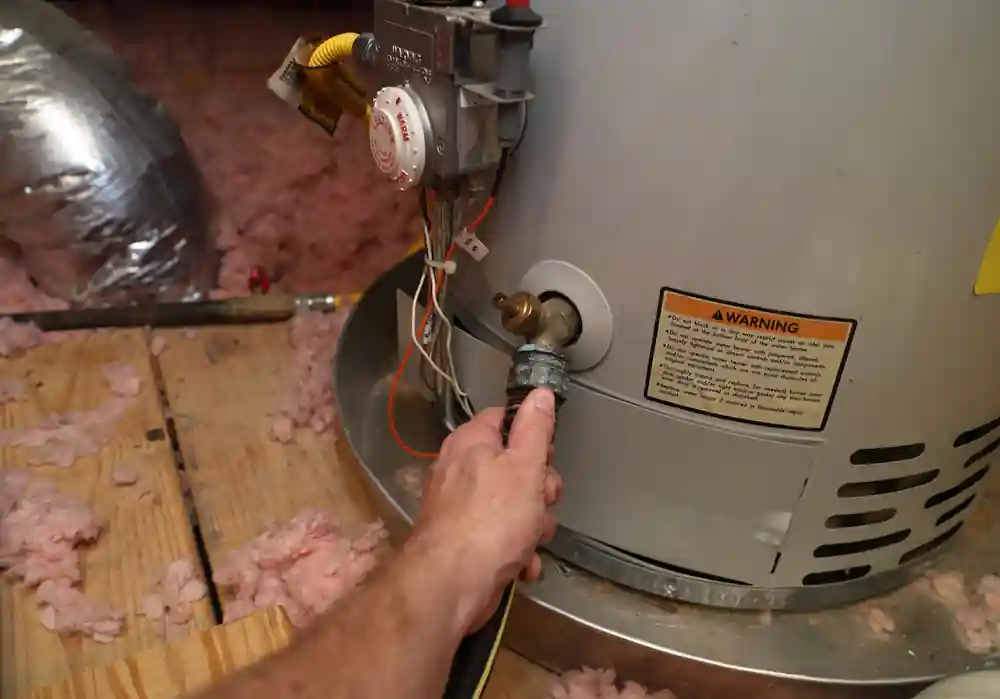 plumber inspects older water heater water line in attic